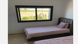 A bedroom with two beds, a window, and a view of a field. - Magnificent sea-view and waterfront apartment at Tamaris Dar Bouazzza (Tamaris)