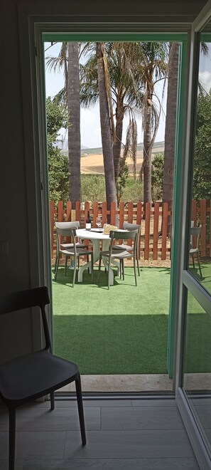 A patio with a table and chairs, a wooden fence, and palm trees. - Villa Degli Alberi with Garden, Private Terrace, Wi-Fi and Air Conditioning (Buseto Palizzolo)