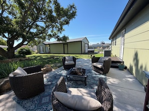 Eine Terrasse mit Korbmöbeln, einer Feuerstelle und einem großen Baum.