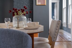 A dining table set with white plates, bowls, and a clear glass vase with red flowers. - Boutique Italian Village OSU 4BR + 4 parking spots (Columbus)
