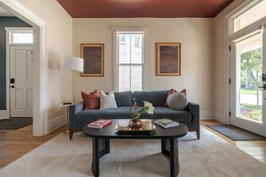 A living room with a blue sofa, a coffee table, and two framed pictures on the wall. - Boutique Italian Village OSU 4BR + 4 parking spots (Columbus)