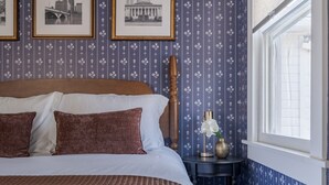 A bedroom with a large bed, a nightstand with a vase, and a window with a view. - Boutique Italian Village | OSU | 4BR | + 2 parking (Columbus)