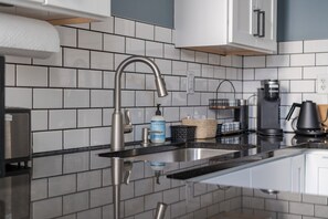 A modern kitchen with a stainless steel faucet, a coffee maker, and a hand soap dispenser on the counter. - Boutique Italian Village OSU 4BR + 4 parking spots (Columbus)
