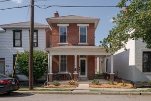 A two-story house with a front porch, a garage, and a driveway. - Boutique Italian Village OSU 4BR + 4 parking spots (Columbus)