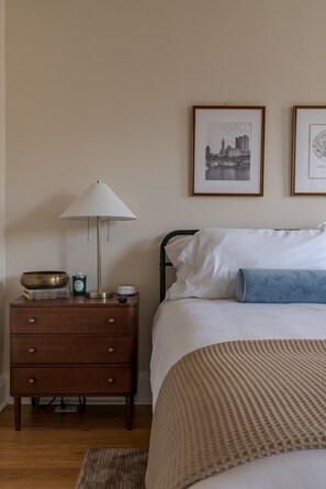A bedroom with a bed, a bedside table with a lamp, a nightstand, and two framed pictures on the wall. - Boutique Italian Village OSU 4BR + 4 parking spots (Columbus)