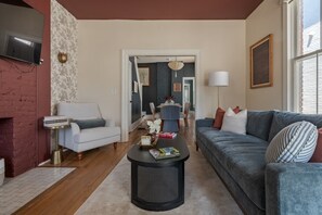 Ein Wohnzimmer mit Sofa, Sessel, Couchtisch und Kamin.
