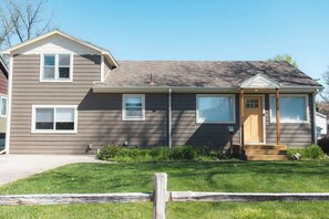 Une maison à deux étages avec un porche à l’avant, un garage et une pelouse bien entretenue.