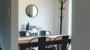 Un coin repas avec une table en bois, des chaises noires, un miroir et un porte-manteau.