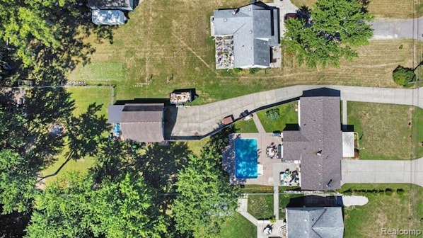 Vista aérea de una zona residencial con piscina, un porche cubierto y garaje independiente.