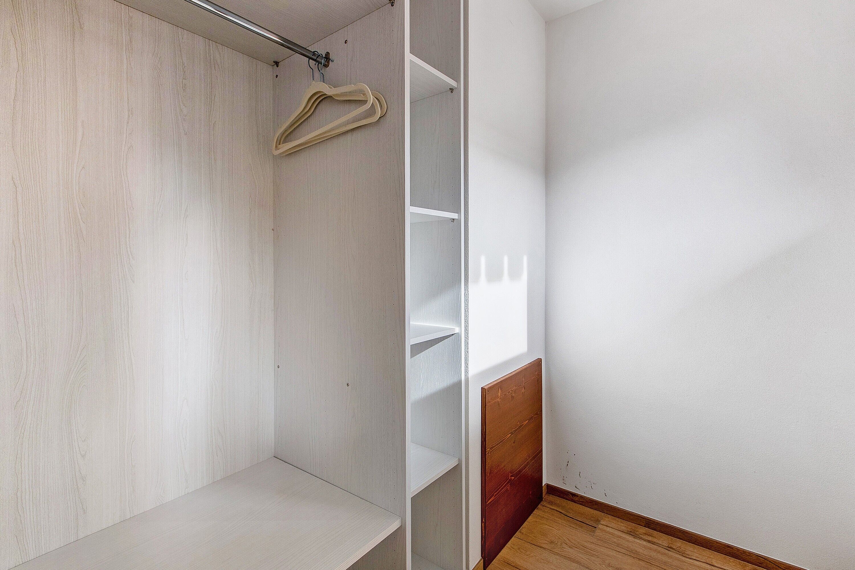 Un dressing avec des étagères en bois et une tringle pour suspendre les vêtements.
