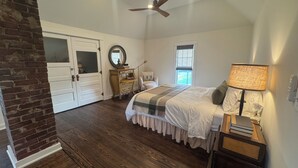 Un dormitorio con cama, mesita de noche, lámpara, cómoda y ventilador de techo.