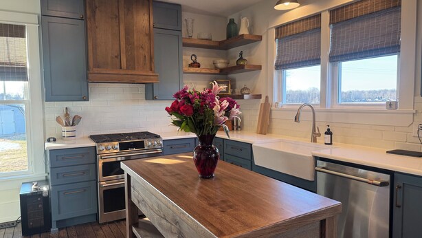 Una cocina moderna con armarios azules, una isla de madera y un jarrón con flores.