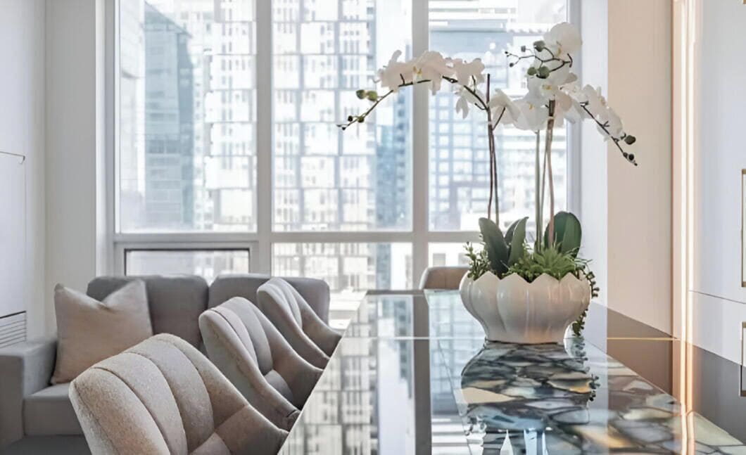 Uma sala de estar moderna com um sofá, uma mesa de centro de vidro e um vaso de planta.