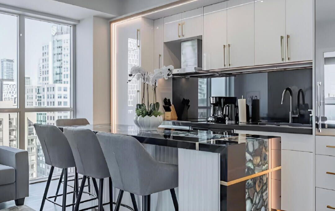 A modern kitchen with a central island, bar stools, and a view of the city.