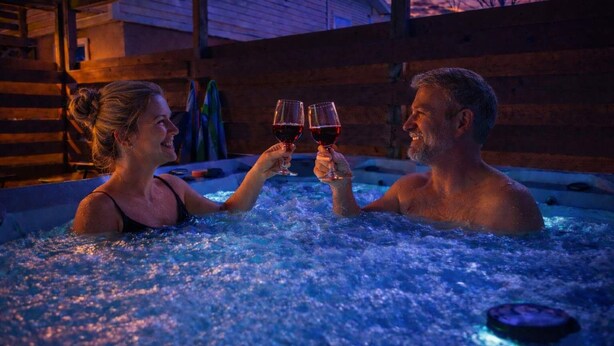 Two people in a hot tub with a wooden cabin in the background. - Walk to Downtown, Hot Tub, Game Room, Boat Parking (Branson)
