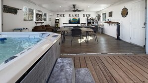 A spacious indoor area with a hot tub, wooden flooring, a dining table, and a ceiling fan. - Walk to Downtown, Hot Tub, Game Room, Boat Parking (Branson)