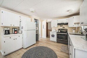 A modern kitchen with white cabinetry, a built-in oven, and a microwave.