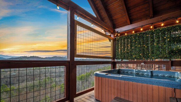 Una terraza de madera con un jacuzzi, vistas del paisaje y un techo de madera.