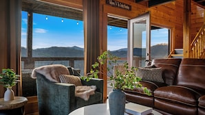 Una habitación acogedora con vistas a montañas, techo de madera y un cartel de bienvenida.