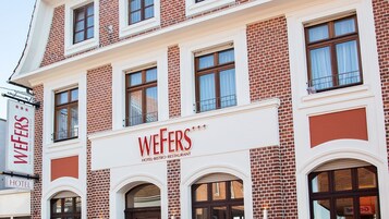 Un edificio de varios pisos con un cartel llamativo que dice 'WEFERS HOTEL, BISTRO, RESTAURANT' en la fachada.
