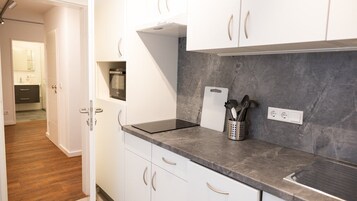 Una cocina moderna con armarios blancos, encimera de granito y horno empotrado.