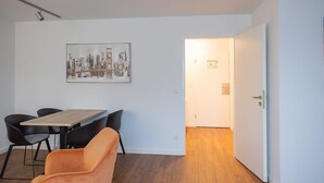 A room with a dining table, chairs, a framed cityscape artwork, and a door leading to another room. - Hotel & Restaurant Wefers (Emsdetten)