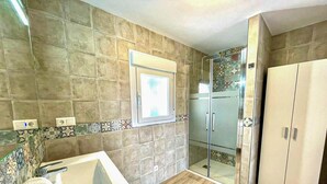 Ein Badezimmer mit einer Badewanne, einer Duschkabine aus Glas und einem Kleiderschrank.
