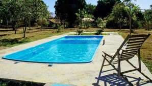 A rectangular swimming pool with a wooden deck and a single wooden chair. - Rustic Farm with Pool Near Curvelo (Corinto)