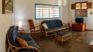 A living room with wicker furniture, a sofa, a loveseat, and a television on a wooden cabinet. - Rustic Farm with Pool Near Curvelo (Corinto)