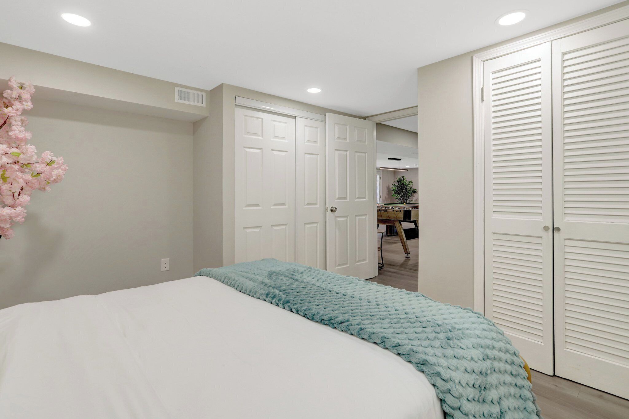 A bedroom with a bed, a closet, and a bathroom in the background.