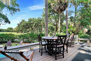 A wooden deck with a round table and chairs, surrounded by lush greenery and trees. - Walk to Beach + Golf Views | Palmetto Dunes (Hilton Head Island)