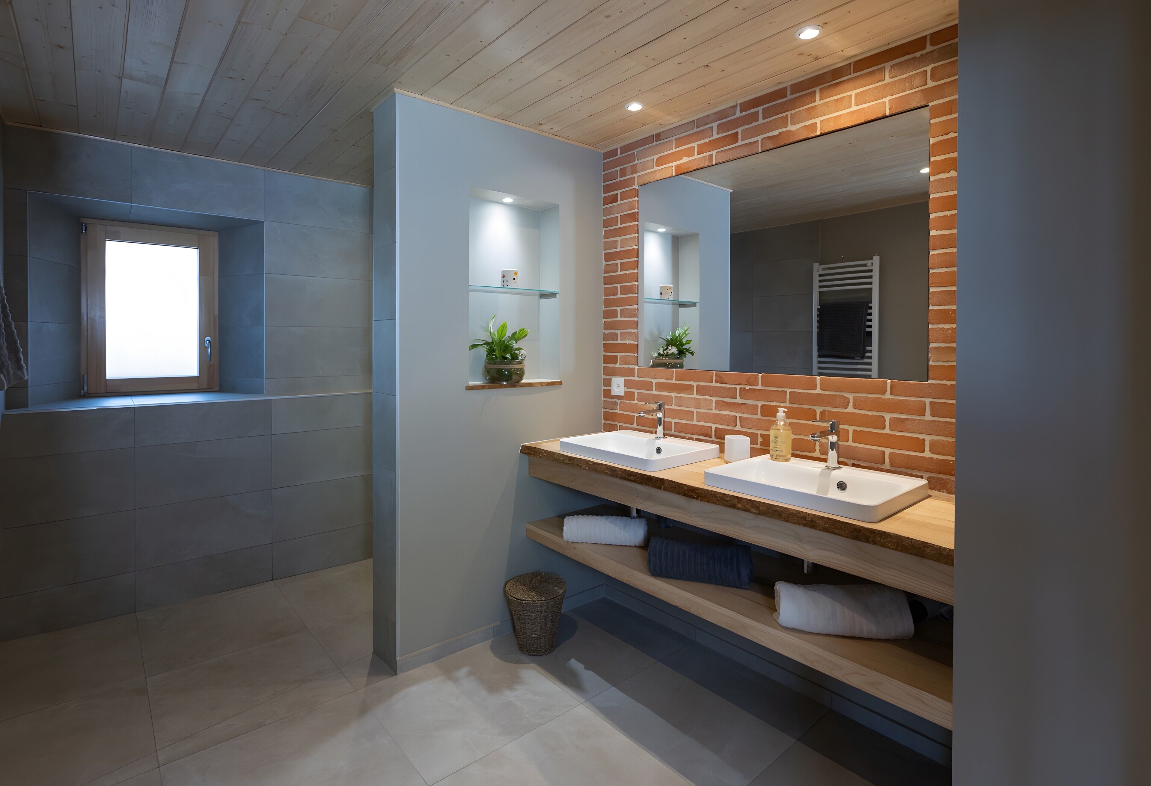 A modern bathroom with two sinks, a large mirror, and a window.