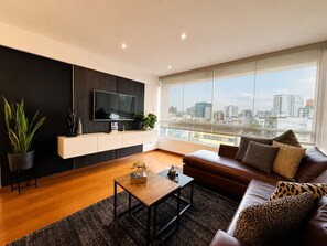 A modern living room with a large window, a flat-screen TV, a sofa, and a coffee table. - RICARDO PALMA - MIRAFLORES (Lima)