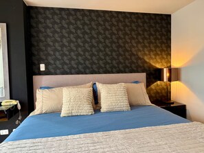 A hotel room with a bed, a nightstand, a lamp, and a geometric-patterned wall. - RICARDO PALMA - MIRAFLORES (Lima)