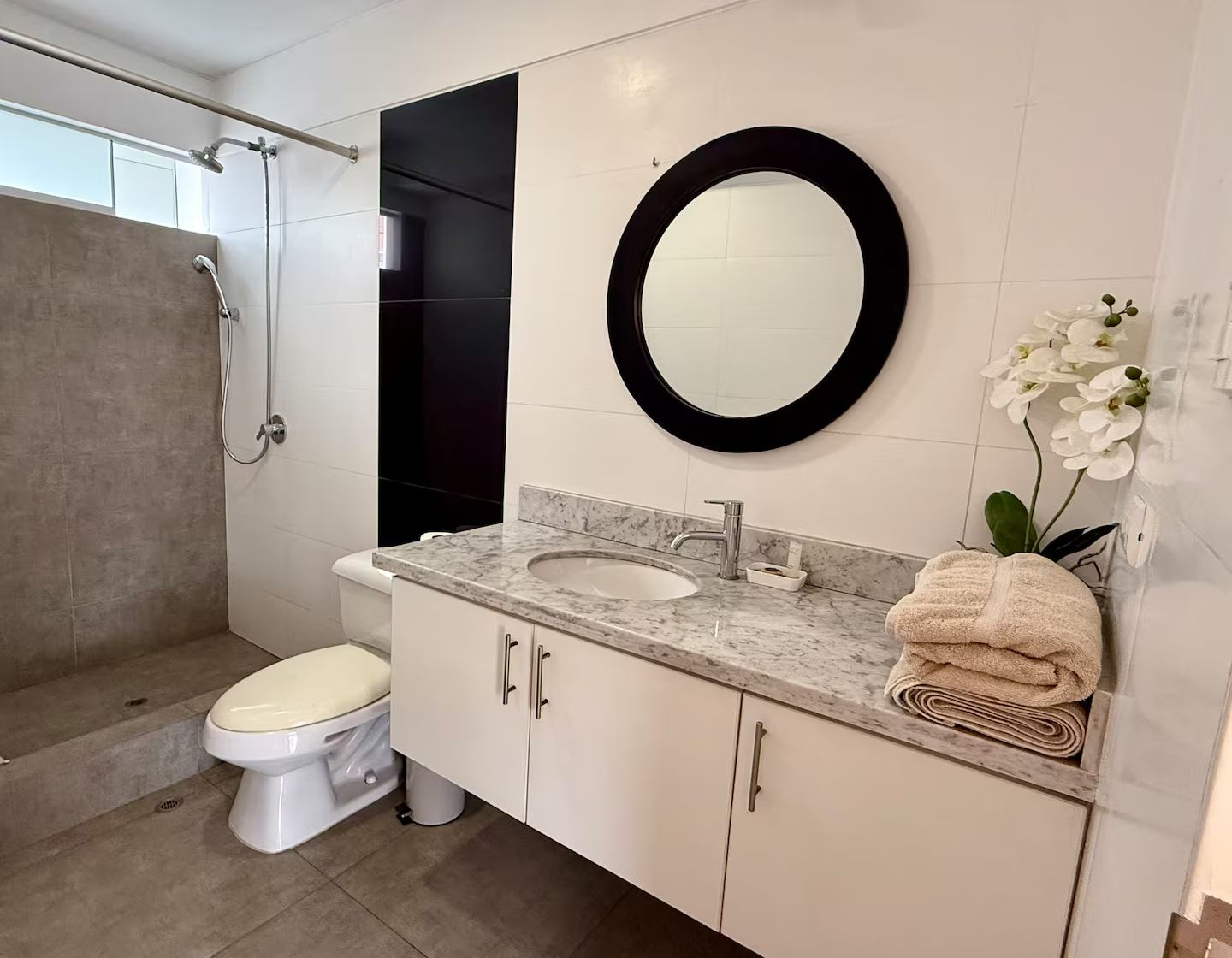 A modern bathroom with a toilet, sink, and shower.
