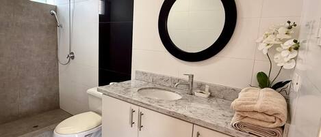 A modern bathroom with a toilet, sink, and shower.