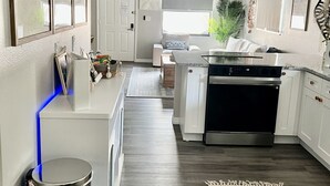 A modern kitchen with a central island, a ceiling fan, and a view into the living area.