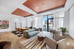 Un salon moderne comprenant un canapé, des fauteuils, une table à manger et une grande fenêtre donnant sur la ville.