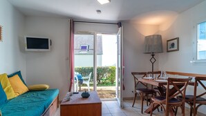 Ein Zimmer mit einem Bett, einem Holztisch, einem Fernseher und einem Essbereich mit Stühlen und Tisch.