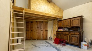A room with a wooden ladder, a shovelful of dirt on the floor, and a wooden cabinet with drawers. - L’Écrin des Neiges - Proche Station de Ski (Fontrabiouse)
