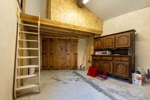 Ein Zimmer mit einer Holzleiter, einer Schaufel Erde auf dem Boden und einem Holzkasten mit Schubladen.