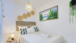 A neatly arranged bedroom with a bed, bedside lamp, and a painting on the wall. - Ti Caz la Zac - Parking Privé (La Riviere)
