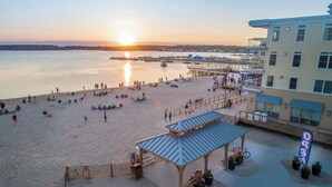 Een strand met een kiosk, een pier en een gebouw met een bord.