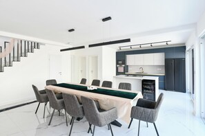 A modern kitchen with a central island, white walls, and a staircase leading to another level.