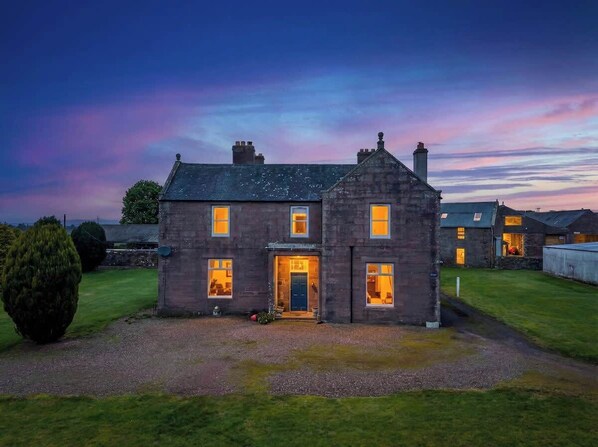 A two-story stone house with a well-maintained lawn in front.