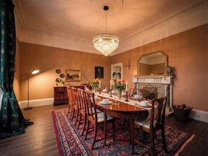 A formal dining room with a chandelier, wooden dining table, chairs, and a patterned rug.