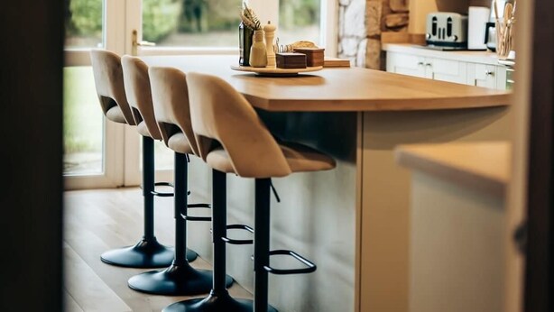 Una cocina moderna con una isla central, taburetes de bar e iluminación colgante.