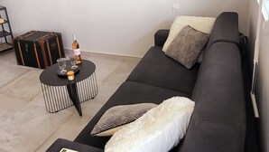 En moderne stue med en sort sofa, et rundt sofabord og en kuffert.