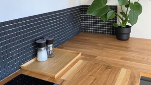 A kitchen with a black and white tiled backsplash, a wooden countertop, a potted plant, and a black induction cooktop. - Superb architect-designed apartment with magnificent view of Marseille (Marseille)