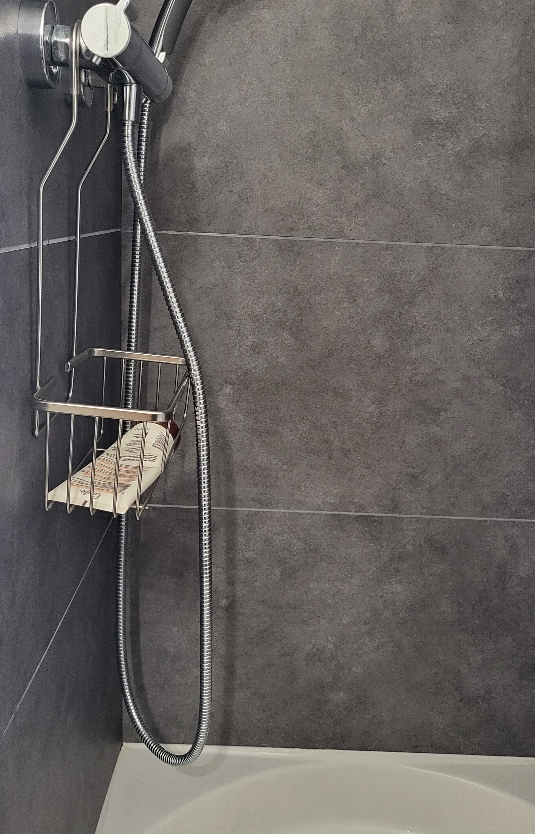 A bathroom with a shower, a metal rack, and a white bathtub.